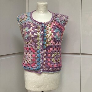 May include: A sleeveless crocheted vest with a button fastening. The vest is made using a granny square pattern in shades of pink, purple, blue, and green.