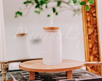 May include: A frosted glass tumbler with a bamboo lid and a glass straw. The tumbler is sitting on a wooden cutting board with a handle.