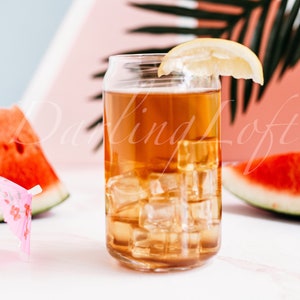 May include: A glass of iced tea with a lemon wedge and ice cubes. Two slices of watermelon are on either side of the glass. A pink paper umbrella is in the glass.