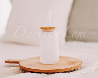 May include: A frosted glass tumbler with a bamboo lid and a glass straw. The tumbler is sitting on a wooden cutting board.