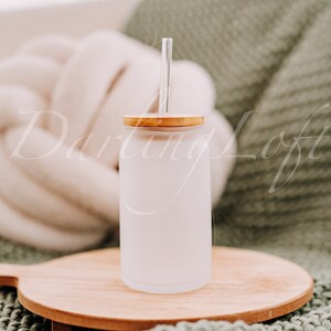 May include: A frosted glass water bottle with a bamboo lid and a clear glass straw. The bottle is sitting on a wooden chopping board.
