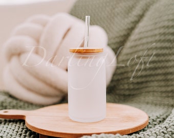 May include: A frosted glass water bottle with a bamboo lid and a clear glass straw. The bottle is sitting on a wooden cutting board.