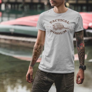 May include: A white t-shirt with a brown armadillo graphic and the text "Tactical Possum" printed on the front.