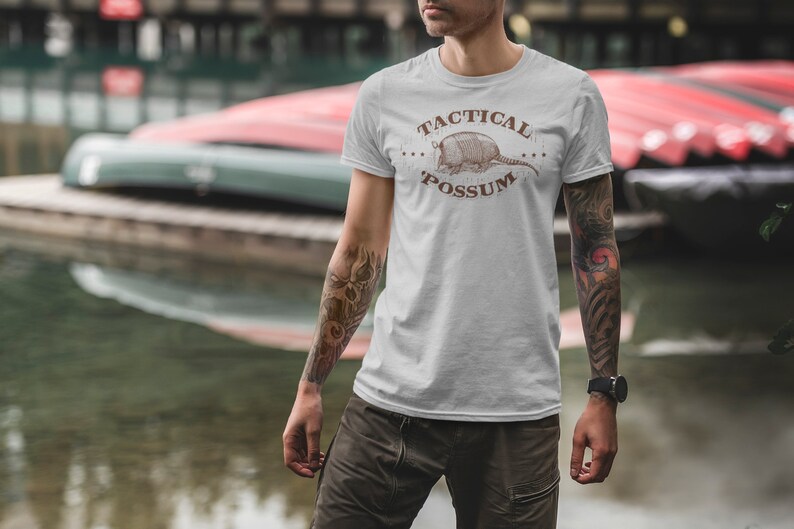 May include: A white t-shirt with a brown armadillo graphic and the text "Tactical Possum" printed on the front.