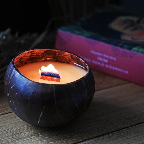 Handmade soy wax candle in a coconut shell with a wooden wick