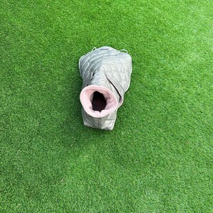 May include: A gray quilted dog coat with a pink fleece lining. The coat has a zipper closure and a loop for attaching a leash.