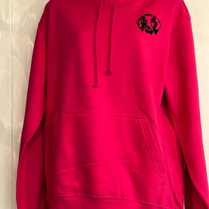 Op de afbeelding: Een roze hoodie met een geborduurd zwart silhouet van een teckel op de voorkant.