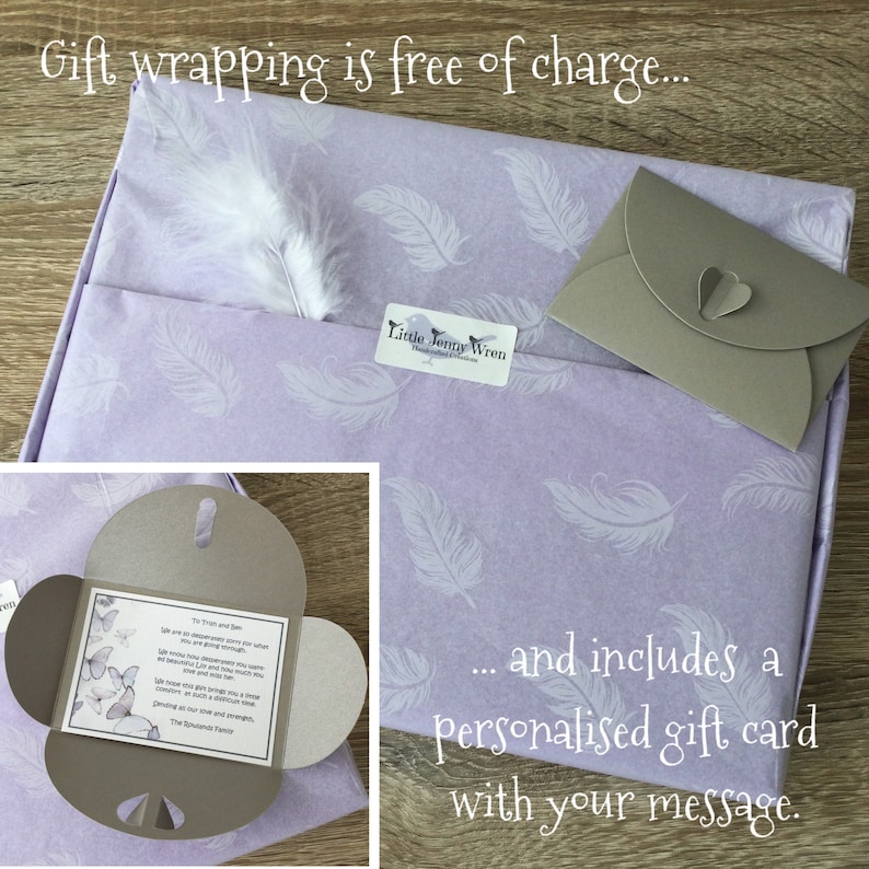 May include: A gift wrapped in lavender paper with white feather and feather pattern. Includes a personalized gift card and a small envelope. The text on the gift card is not clear.