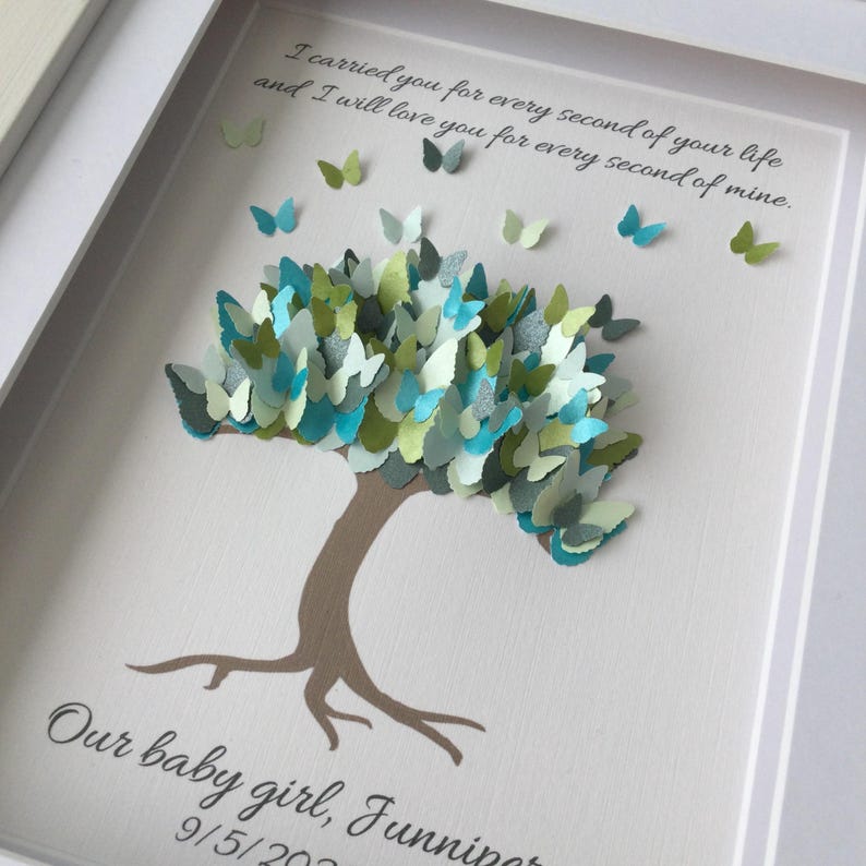 May include: A framed artwork featuring a tree crafted from paper butterflies in shades of blue, green, and white. The tree's trunk is brown, and the background is white. Text at the top reads, "I carried you for every second of your life and I will love you for every second of mine."