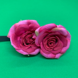 Peut inclure: Deux roses en tissu rose attach&eacute;es &agrave; un bandeau noir. Les roses sont superpos&eacute;es et ont un aspect r&eacute;aliste.