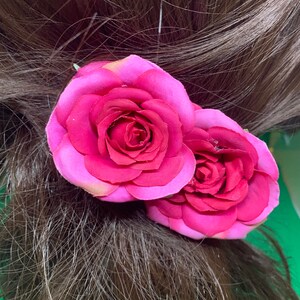 Peut inclure: Deux roses en tissu rose avec un centre rose fonc&eacute; sont attach&eacute;es &agrave; une barrette de cheveux brune.