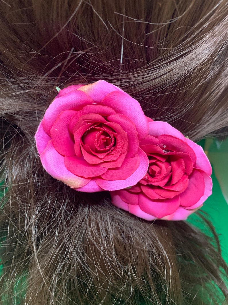 Peut inclure: Deux roses en tissu rose avec un centre rose fonc&eacute; sont attach&eacute;es &agrave; une barrette de cheveux brune.