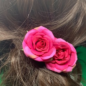 Peut inclure: Deux roses en tissu rose avec une tige verte, attach&eacute;es &agrave; une pince &agrave; cheveux.