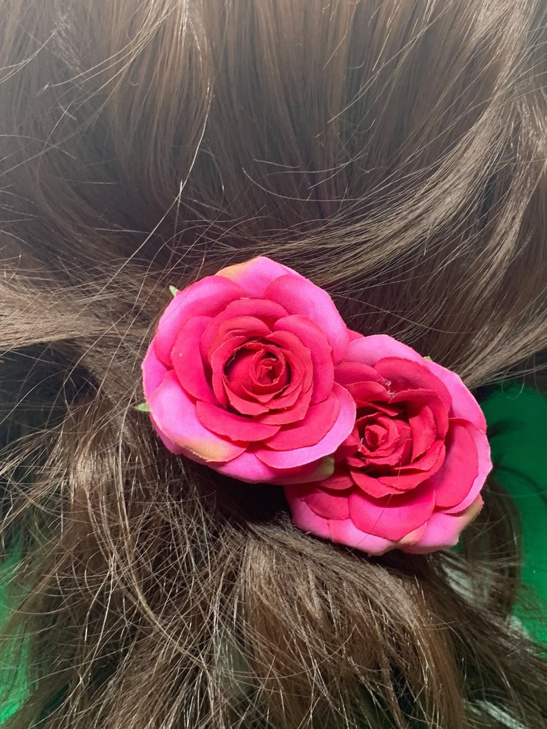 Peut inclure: Deux roses en tissu rose avec une tige verte, attach&eacute;es &agrave; une pince &agrave; cheveux.