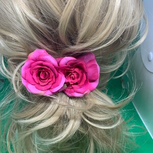 Peut inclure: Deux pinces &agrave; cheveux en forme de rose en tissu rose. Les roses sont attach&eacute;es &agrave; une pince qui peut &ecirc;tre utilis&eacute;e pour maintenir les cheveux en place.