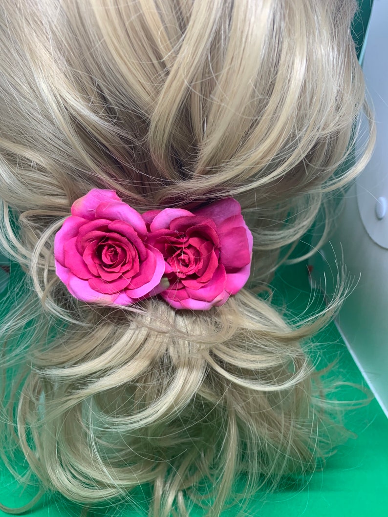 Peut inclure: Deux pinces &agrave; cheveux en forme de rose en tissu rose. Les roses sont attach&eacute;es &agrave; une pince qui peut &ecirc;tre utilis&eacute;e pour maintenir les cheveux en place.