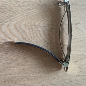 Peut inclure: Une pince &agrave; cheveux en m&eacute;tal argent&eacute; avec un &eacute;lastique noir. La pince est ouverte et pr&ecirc;te &agrave; &ecirc;tre utilis&eacute;e.