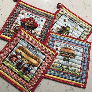 May include: Four square quilted pot holders with red, yellow, and black patterned borders. Each features a different summer-themed graphic: a grill with ladybugs, a bug with a sign, a hot dog with ladybugs, and a hamburger with a bug.