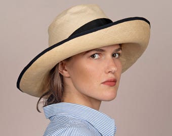 A ladies’ straw hat made from the exquisite Bakou, featuring a wide black hatband. An elegant, handmade, one-of-a-kind hat called Calla.