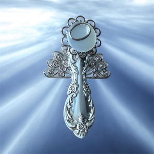 May include: A handcrafted angel figurine made from repurposed silverware. The angel features a spoon body with intricate floral detailing, delicate wings, and a round, light blue gemstone head. The wings and head are adorned with silver accents.
