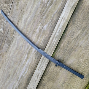 Può includere: Una spada katana nera con una lama curva e un'impugnatura strutturata. La spada è in metallo e ha una guardia vicino all'impugnatura. La lama è lunga circa 76 cm.