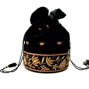 May include: A black velvet drawstring bag with gold embroidery featuring floral designs. The bag has a tassel on each side.