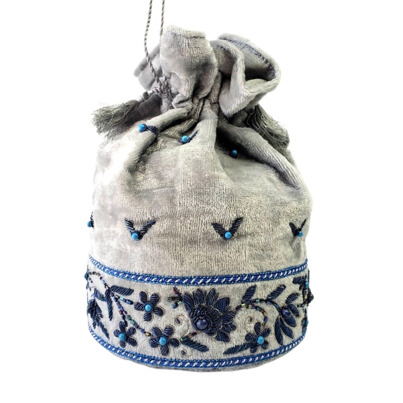 May include: A gray velvet drawstring bag with blue and black embroidery. The bag has a tassel on each side and is decorated with blue beads.