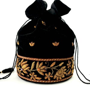 May include: A black velvet drawstring bag with gold embroidery and jewel accents. The bag has a tassel and a floral design around the bottom.