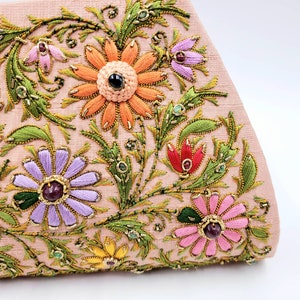 May include: A pink fabric clutch with embroidered floral designs in shades of green, orange, purple, pink, and red. The flowers are embellished with gold and jewel-toned beads.