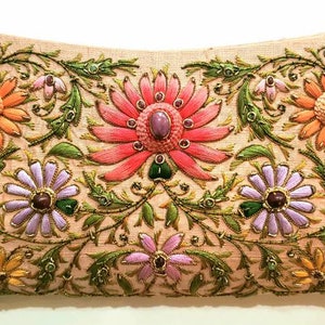 May include: A beige clutch purse with intricate floral embroidery. The flowers are in shades of pink, orange, purple, and green, with gold accents. The purse has a beaded embellishment.