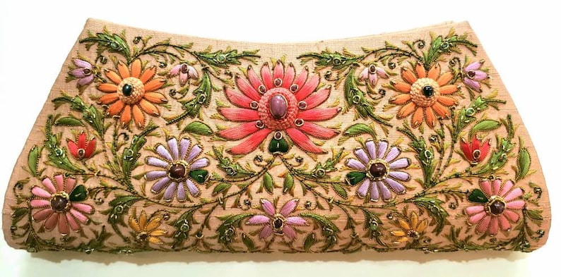 May include: A beige clutch purse with intricate floral embroidery. The flowers are in shades of pink, orange, purple, and green, with gold accents. The purse has a beaded embellishment.
