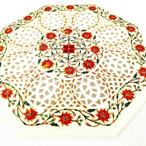 Puede incluir: Tapa de mesa octogonal de m&aacute;rmol blanco con un intrincado dise&ntilde;o de corte y un patr&oacute;n floral rojo.