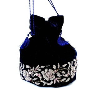 K&ouml;nnte beinhalten: Eine dunkelblaue Samt-Kordeltasche mit einem silbernen und rosafarbenen Blumenstickerei-Design.