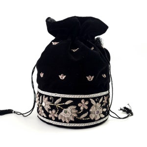 May include: Black velvet drawstring bag with silver and gold embroidery featuring floral designs and pink and green gemstones.