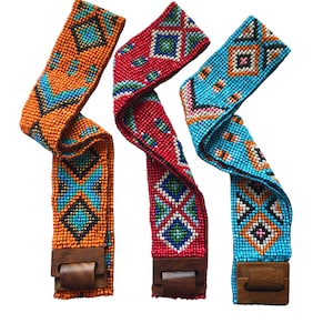 May include: Three beaded belts with geometric patterns in orange, red, and blue with wooden buckles.