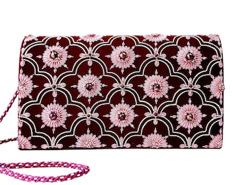 Könnte beinhalten: Eine bordeauxrote Clutch aus Samt mit einem rosafarbenen Blumendesign und einem Perlenriemen. Die Clutch ist mit kleinen, schillernden Edelsteinen verziert.