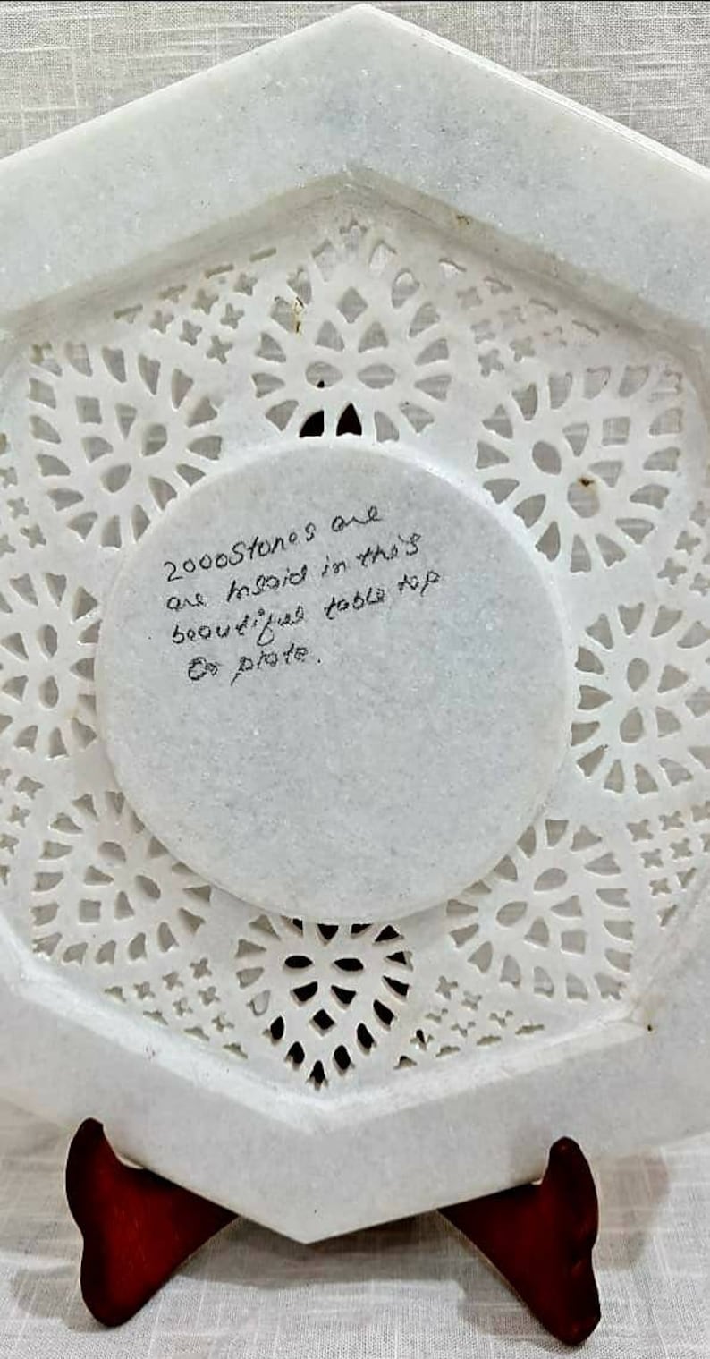 Puede incluir: Mesa de m&aacute;rmol blanco con intrincados dise&ntilde;os recortados. La parte posterior de la mesa tiene una nota escrita a mano que dice: "2000 piedras est&aacute;n incrustadas en esta hermosa mesa.  Do plate."