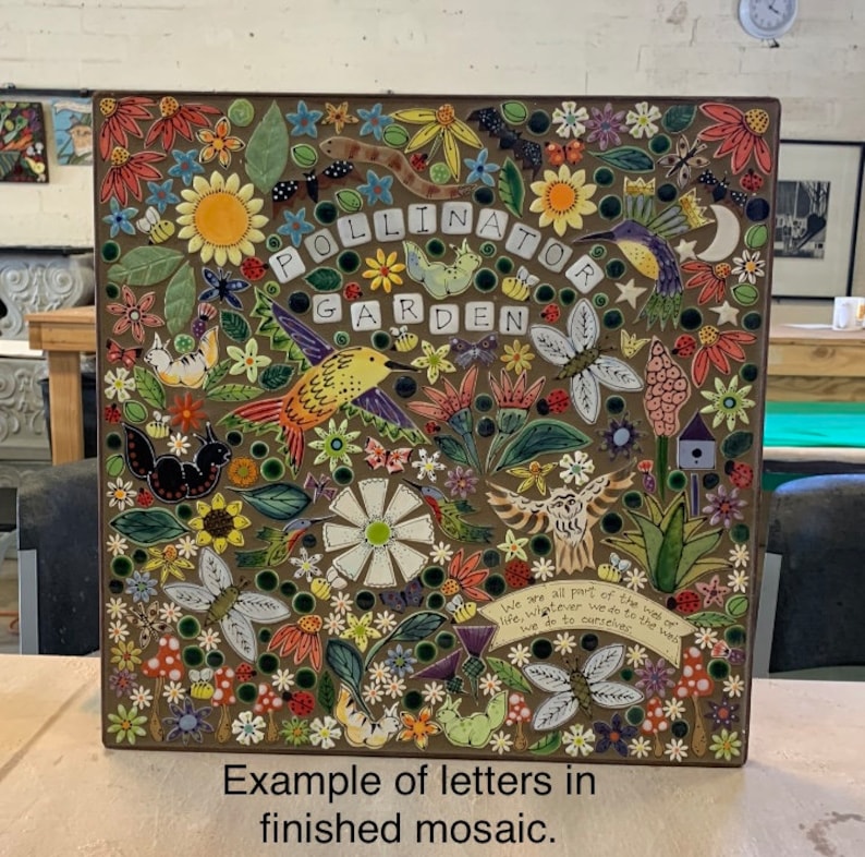 May include: A colorful mosaic tile art piece with the words "Pollinator Garden" in the center. The mosaic features a variety of flowers, butterflies, hummingbirds, and other nature-inspired elements. The text "We are all part of the web of life, whatever we do to the web, we do to ourselves." is included in the mosaic.