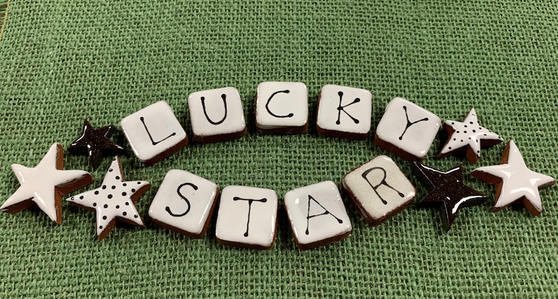 May include: White ceramic tiles spelling out "LUCKY STAR" with black lettering.  The tiles are surrounded by small white and black ceramic stars.