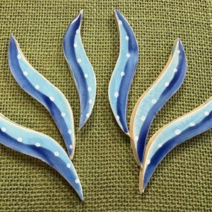 May include: Five curved, wave-shaped ceramic tiles featuring a glossy finish. Each tile displays a gradient of dark blue to light blue with a central row of small, white hand-painted dots running along the length of the curved surface.