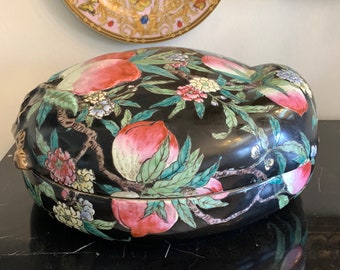 May include: A black oval-shaped porcelain box with a lid, decorated with hand-painted peach blossoms and leaves in shades of pink, green, and white.