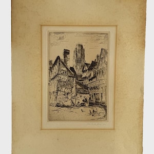 May include: A black and white etching on aged paper depicting a European town square with timber-framed buildings, a tall central church tower, and figures in the foreground. The print features intricate line work, visible text on a building facade, and a signature in the bottom right corner.