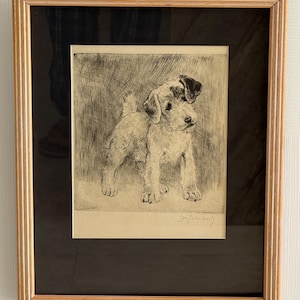 May include: A framed black and white etching of a terrier dog. The dog is standing, with its head turned slightly to the right. The artwork is in a gold-colored wooden frame with a black matting.