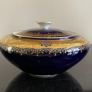 以下が含まれることがあります： コバルトブルーの磁器製の砂糖入れ。金色の蓋と複雑な金色の縁取りが施されています。丸い形をしていて、繊細な花柄が描かれています。