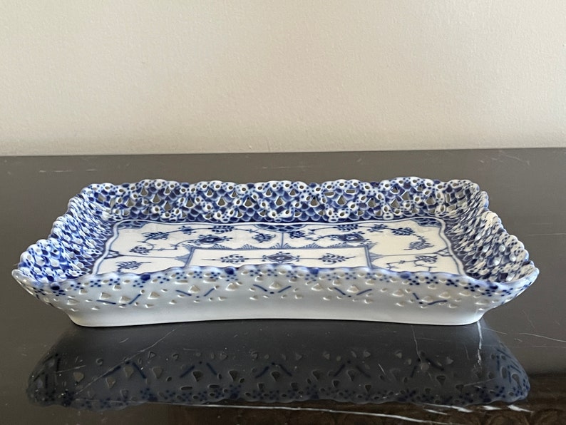 May include: A white porcelain serving tray with a blue and white floral pattern and a lace-like border.