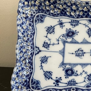 May include: A square blue and white porcelain serving tray with a delicate openwork lace design around the edge. The tray features a traditional blue and white floral pattern.