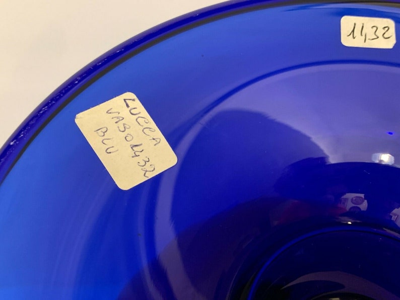 Puede incluir: Un cuenco de vidrio azul oscuro con una etiqueta que dice "Lucca Vaso 4332 Blu". El cuenco tiene el n&uacute;mero "4132" escrito en el lateral.