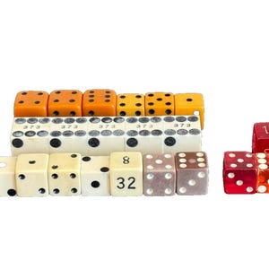 May include: A collection of vintage dice in various colors, including red, orange, white, and brown. The dice have different numbers on each side, including 8, 16, 32, and 373.
