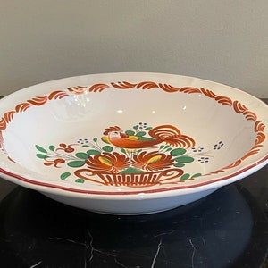 Pode incluir: Tigela de servir oval de cerâmica branca com um desenho de galo e flores pintado à mão. A borda tem uma borda vermelha e detalhes decorativos em laranja e vermelho. Adequado para servir. Cerca de 30 cm de diâmetro.