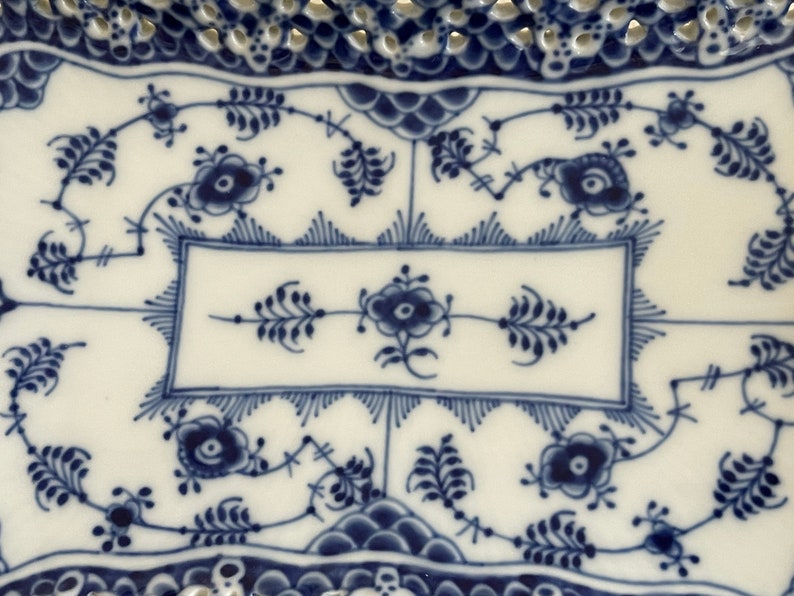 May include: A white ceramic serving dish with a blue and white floral pattern. The dish has a scalloped edge and a raised rim.